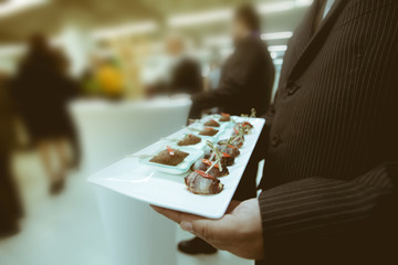 Waiter serving food in luxury dinner party, Blurry background wi