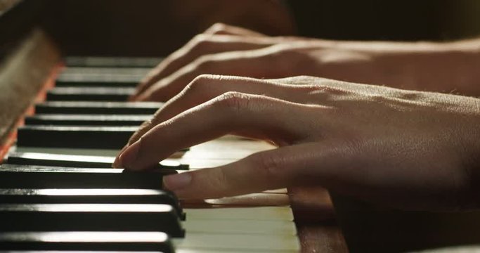 A musician plays the piano reading the score in front of. The musician or composer crushes the piano keys with his long fingers. Concept: sound, music, academy, concert, pianist
