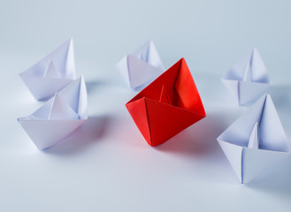 red paper ship leading among white