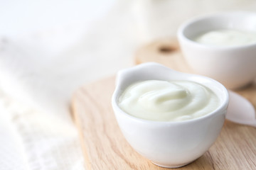 Close up white yogurt in cup on wooden plate