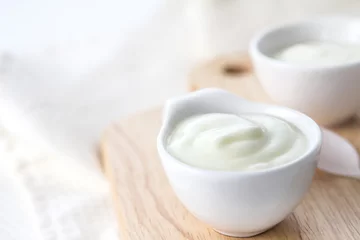 Gardinen Close up white yogurt in cup on wooden plate © Cozine