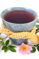 Cup of tea with wild rose flower on white background