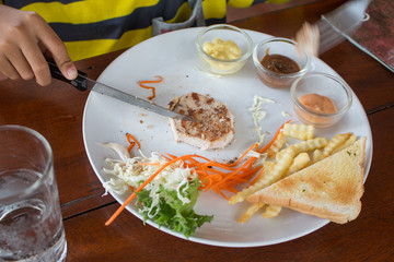 A boy is Eating steak in a restaurant.