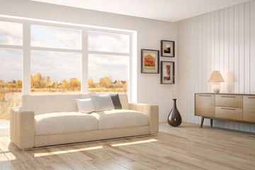 White room with sofa and autumn landscape in window. Scandinavian interior design
