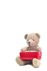 Cute teddy bear sitting and hugging red present gift box on whit