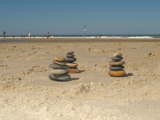 Fototapeta na wymiar Three pyramid of stone or pebbles on the sand in front of the sea or the ocean