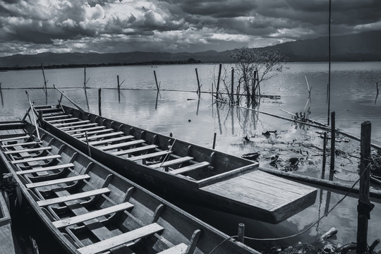 empty twin wooden fishing boat in rain storm in quiet lake sky black and white tone.
