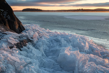 Heap of small cracked ice by a rock at a frozen lake in Finland in the winter.