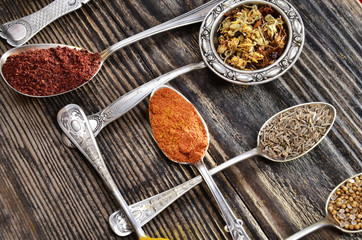 Assortment of spices in vintage spoons on wooden background..