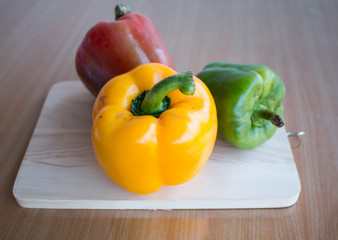 Fresh colorful bell pepper cooking on wooden cut board