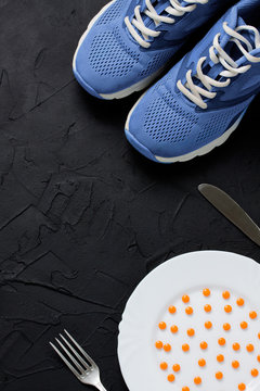 Sport shoes and white plate with orange pills