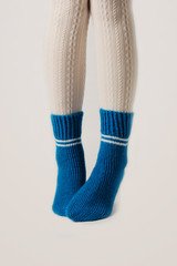 Female legs in white stockings and blue knitted socks.