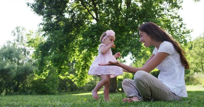 in a sunny summer day A newborn takes its first steps running toward the smiling mother happy and spensierata.I first steps that you never forget in life. And mom helps her to take the first steps.