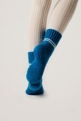 Female legs in white stockings and blue knitted socks.