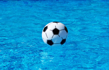 Fototapeta na wymiar Beach ball floating in blue swimming pool. Space for text.