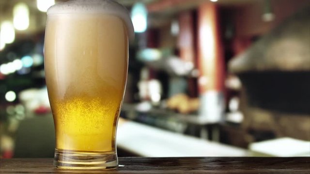 Beer is pouring from the top into the glass. 4K video.