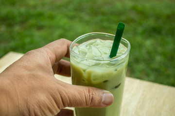 Hand holding Home made Matcha iced green tea with milk, Latte Te