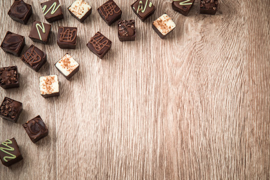 Delicious chocolate candies on the wooden background.
