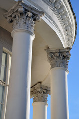 Looking up at a white round classical building with columns and capitals against the blue sky.