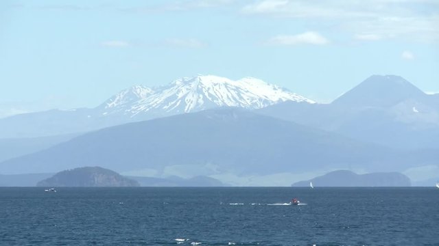 boat passes in front of mountains on Lake Taupo New Zeaaland