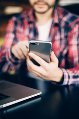 Close up of man in red shirt sitting on sofa by the table with phone