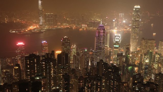 Aerial view of Hong Kong at night with time lapse of Victoria Harbour from Lugard Road Lookout at Victoria Peak, skyscrapers landmarks with their glowing lights.