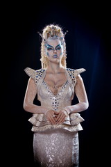 emotional actress woman in makeup and costume queen of elves or snow queen on blue-black background