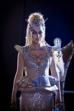 emotional actress woman in makeup and costume queen of elves or snow queen on blue-black background