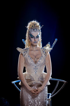 emotional actress woman in makeup and costume queen of elves or snow queen on blue-black background