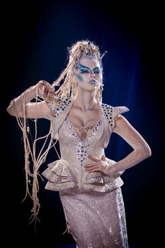 emotional actress woman in makeup and costume queen of elves or snow queen on blue-black background
