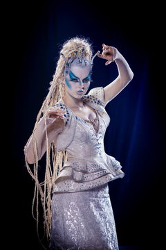 emotional actress woman in makeup and costume queen of elves or snow queen on blue-black background