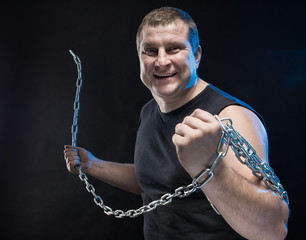 Actor Brutal man with a chain in his hands on a black background.