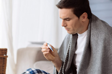 Sad unhappy man holding a thermometer