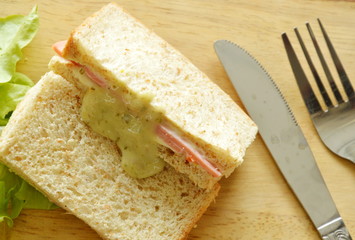 pork bologna whole wheat sandwich with fork and knife on wooden chop block