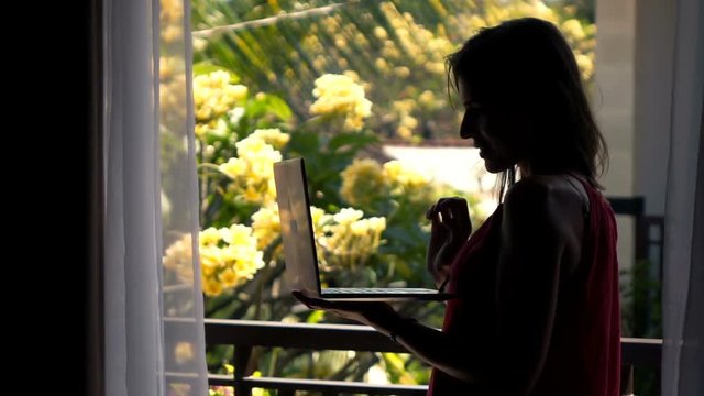 Silhouette of woman with laptop standing on terrace, super slow motion 240fps
