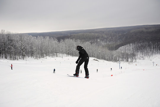Snowboarder in a black suit moves down on a background of a monochrome landscape