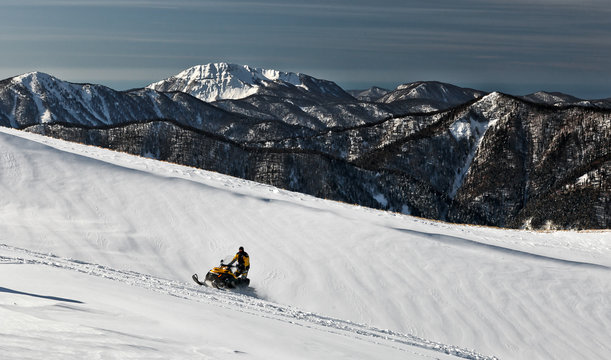 A man on a snowmobile races on snowy expanses. State Nature Reserve in Adygea, Russia.