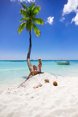 Girl sitting on the beach near palm tree
