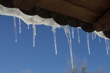 Snowy ice Icicles hanging on a roof house