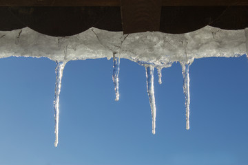 Snowy ice Icicles hanging on a roof house