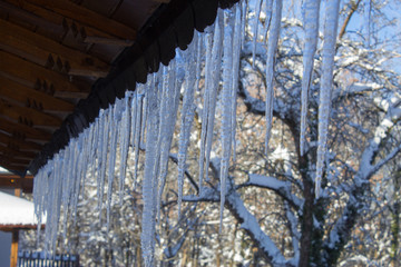 Snowy ice Icicles hanging on a roof house