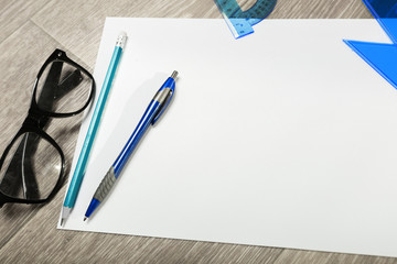 Blank notebook and pencil with glasses on wooden table