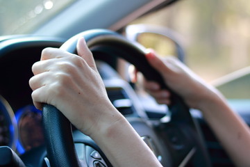 Hand holding on black steering wheel while driving