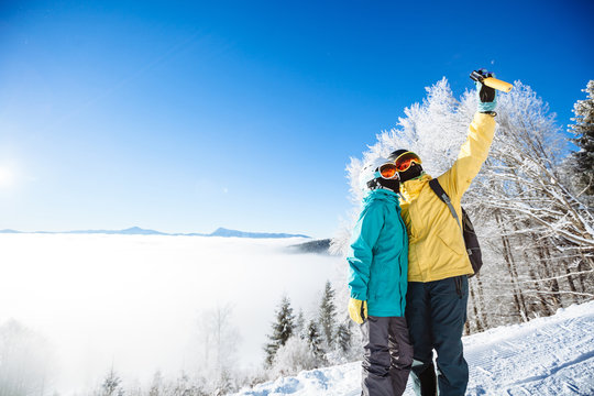 Skiers taking picture of themselves with smart phone over a moun