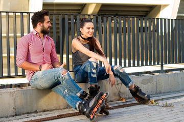 Couple on inline skates sitting. Smiling young woman. Good idea for first date.