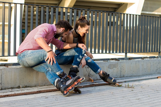 People on rollerblades sitting. Young man and woman laughing. Cool idea for first date.