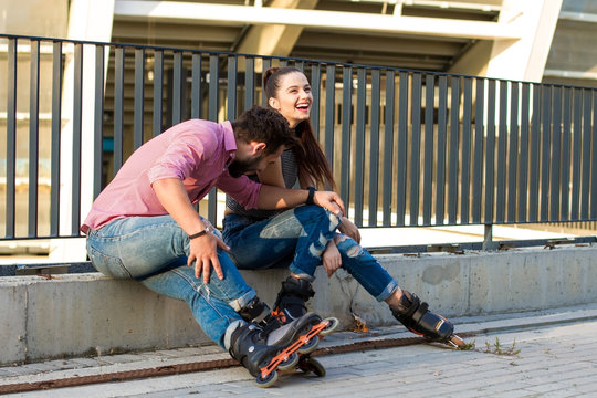 Couple on rollerblades is sitting. Young lady laughing. Our first date.