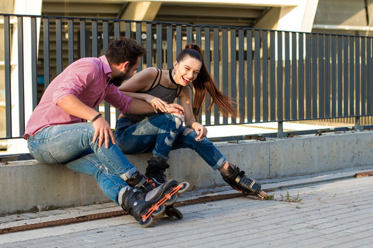 Young woman and man sitting. Lady on rollerblades laughing. Laugh until your belly hurts.