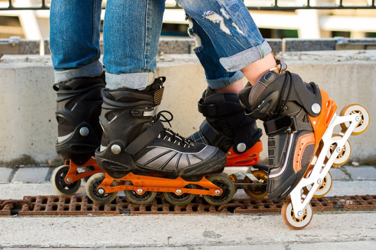 Legs wearing rollerblades. Black and orange inline skates. Improved materials and new design.
