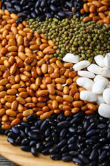 Different color of beans on wooden plate